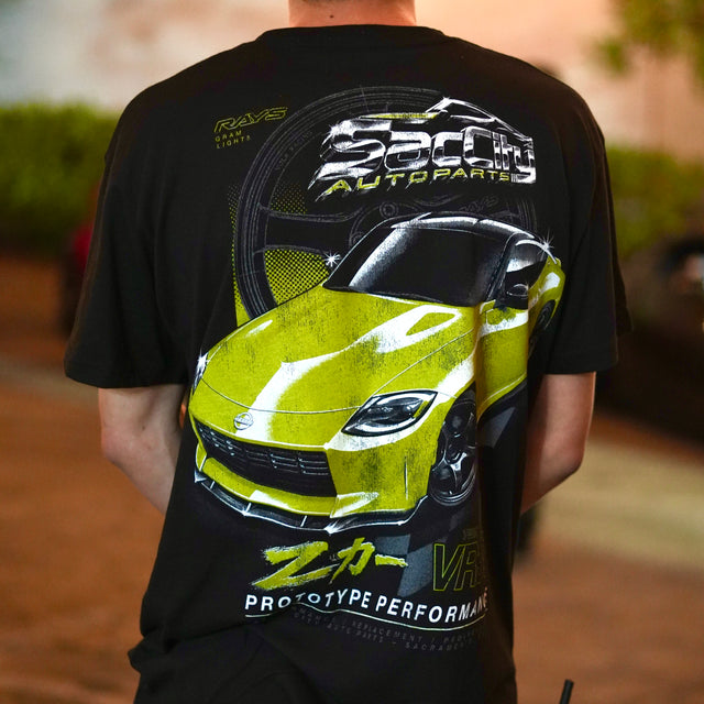 Back of a black Proto Z T-shirt worn outdoors, showing a large yellow Nissan Z and Sac City graphic.