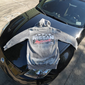 Back of faded grey Motorsports hoodie laid on a car, showing the large white and red Nissan Motorsports graphic.